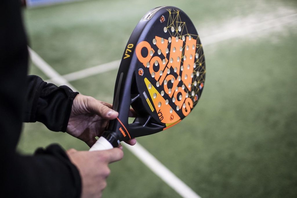 Padelspelers in actie op een baan met geluidsabsorberende schermen om geluid van padel te verminderen
